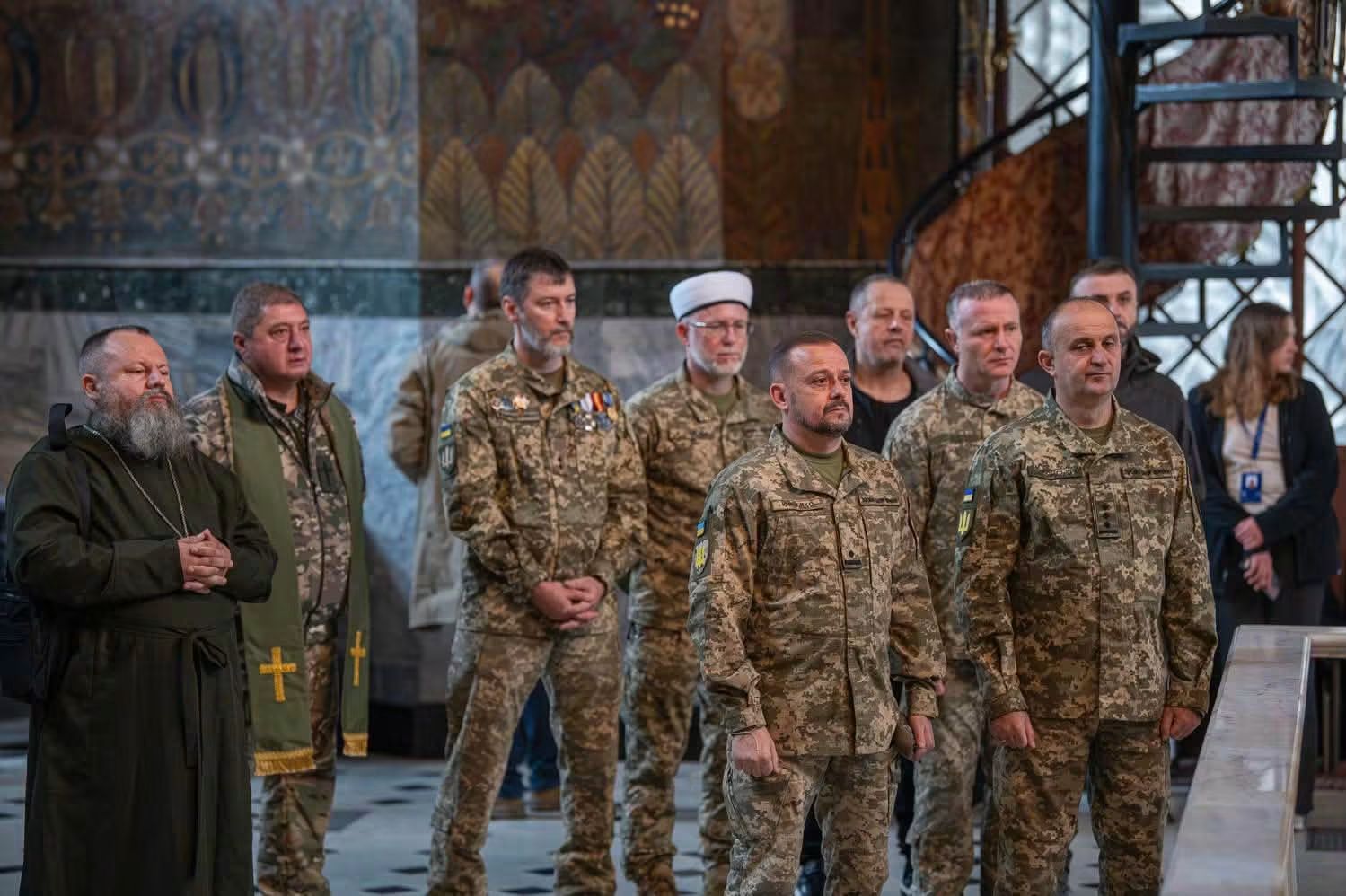 Військові капелани в пікселі, священник у темному підряснику з наперсним хрестом і воїни ЗСУ стоять на молебні в розписаному Трапезному храмі