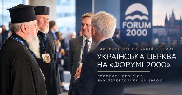Двоє православних ієреїв у чорних камилавках із бейджами учасників розмовляють із двома чоловіками в костюмах біля стенду «Forum 2000» на тлі празьких веж; напис «Митрополит Епіфаній у Празі: Українська Церква на «Форумі 2000» говорить про віру, яку перетворили на зброю»
