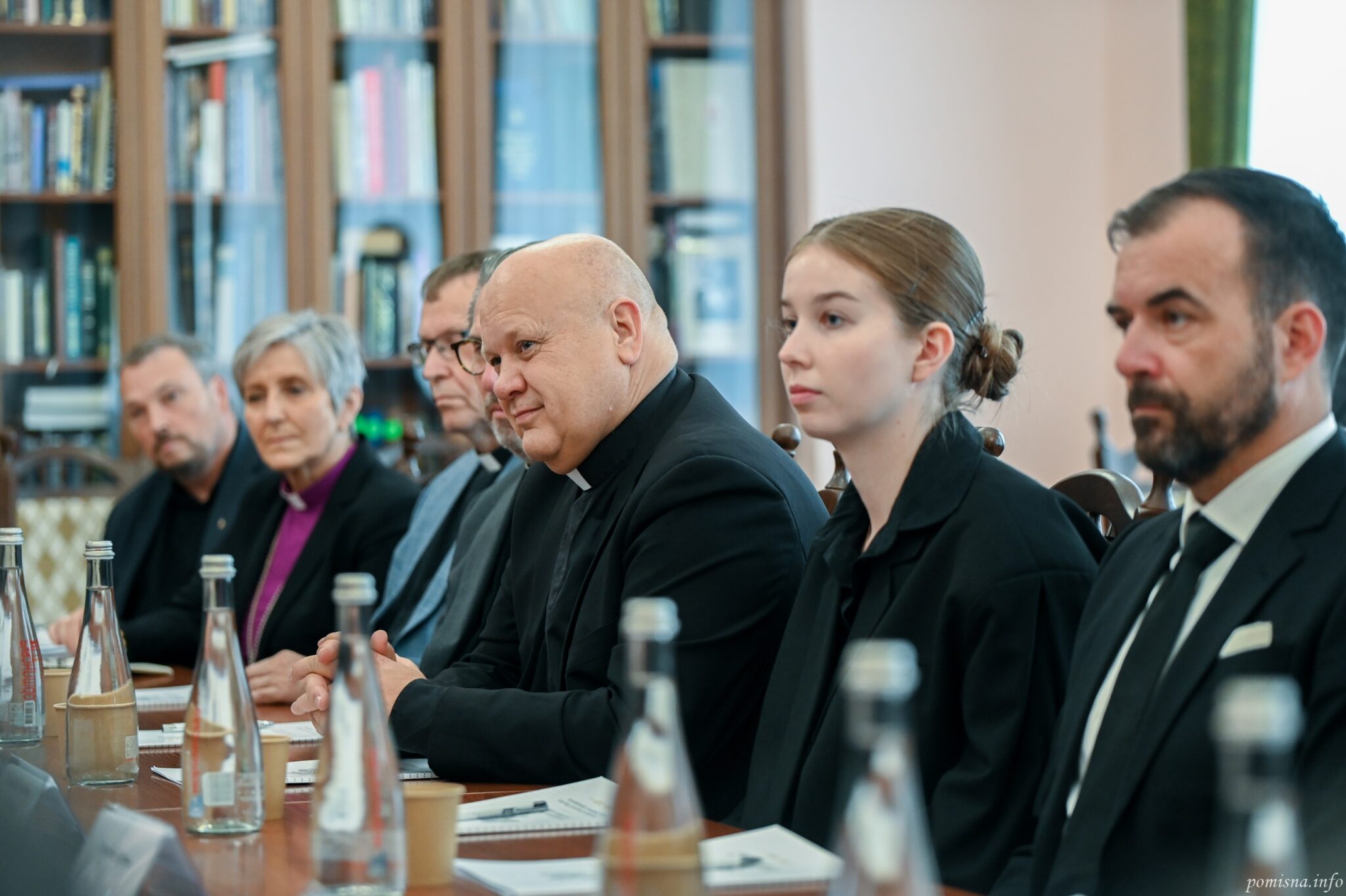 Члени норвезької делегації за столом, серед них єпископ у фіолетовій сорочці